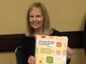 Dr. Catherine Nelson holding a copy of Child-guided Strategies: The Van Dijk Approach to Assessment