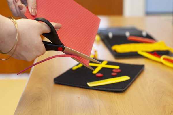 close up of hands cutting red and yellow craft materials