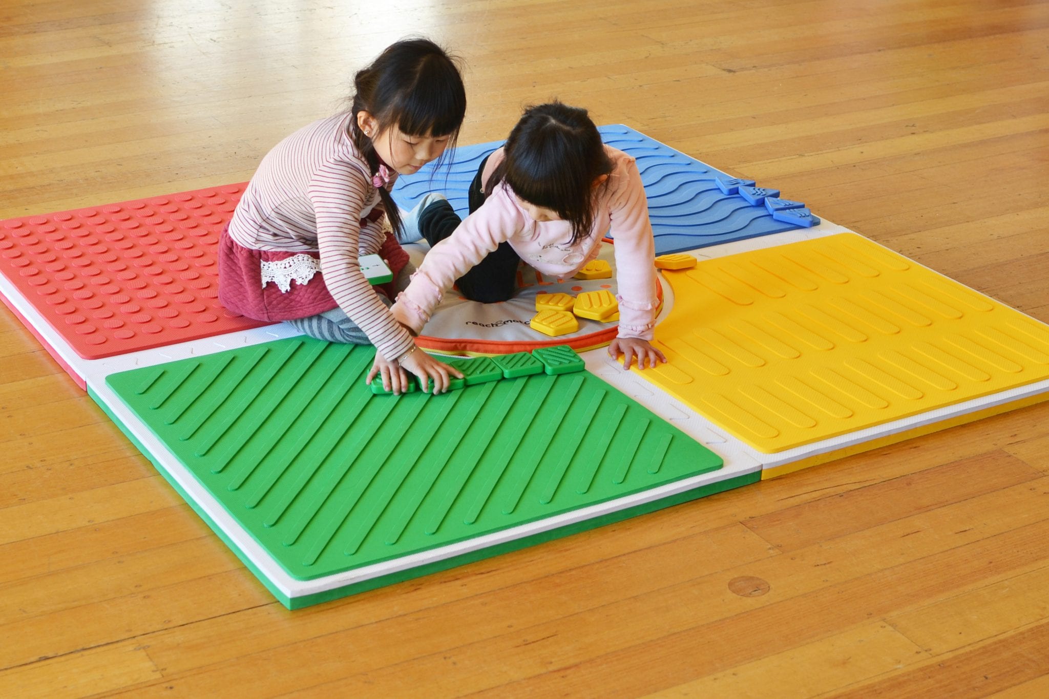Two young girls playing on Reach & Match mat