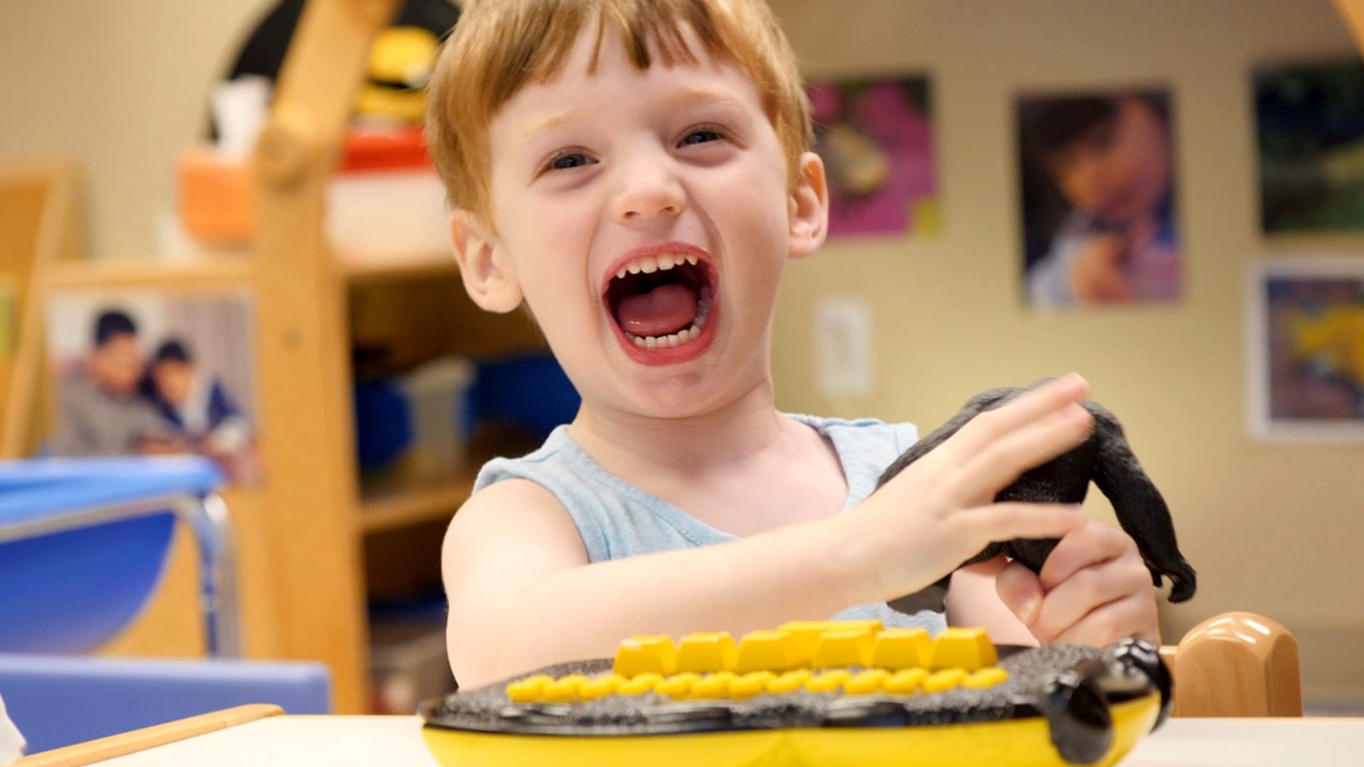 Preschool boy laughs as he plays with APH's Braille Buzz