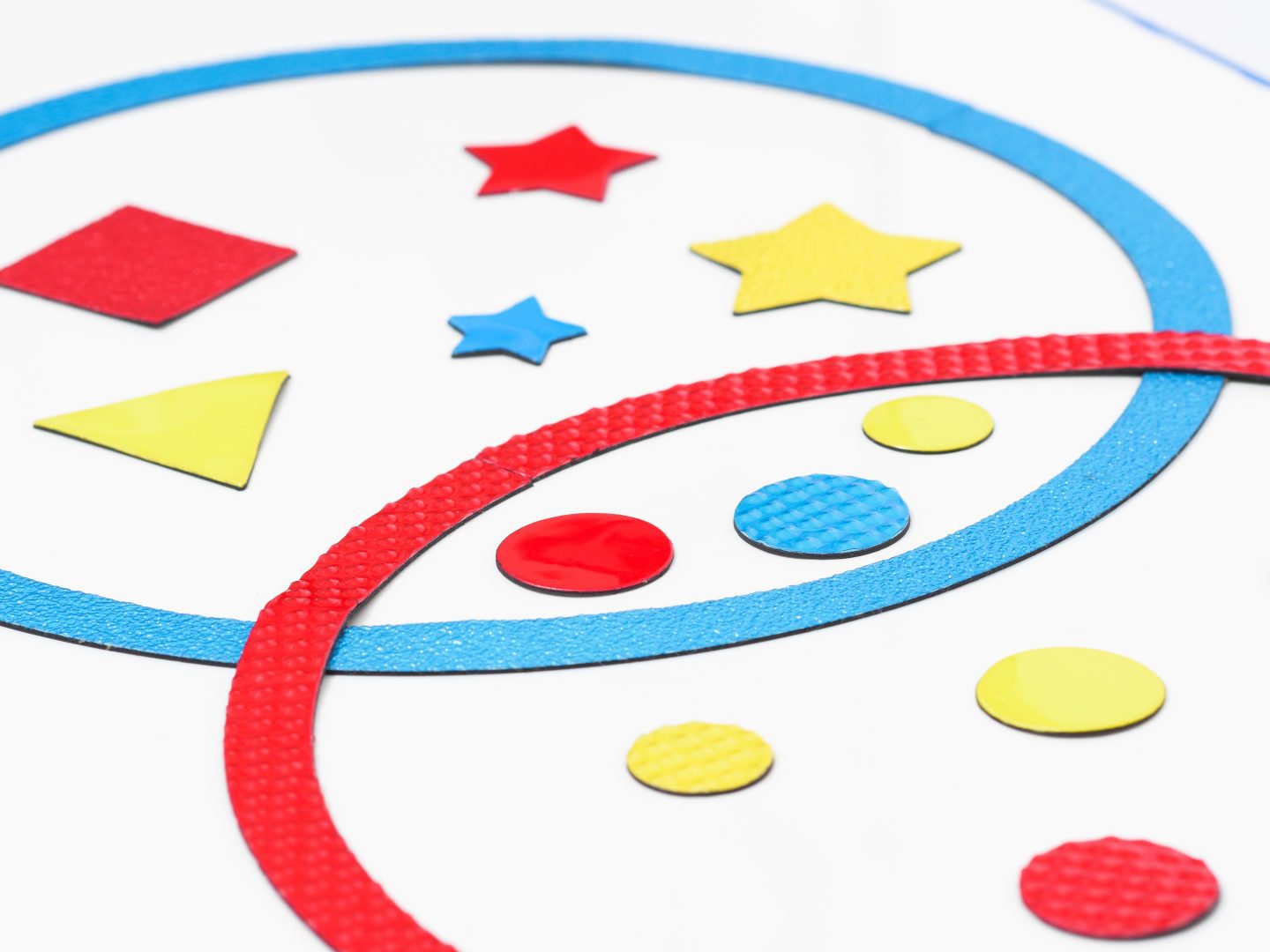 A picture of large textured circles that overlap. Inside are differently textured shapes including stars, circles, triangles, and squares in shades of red, yellow, and blue.