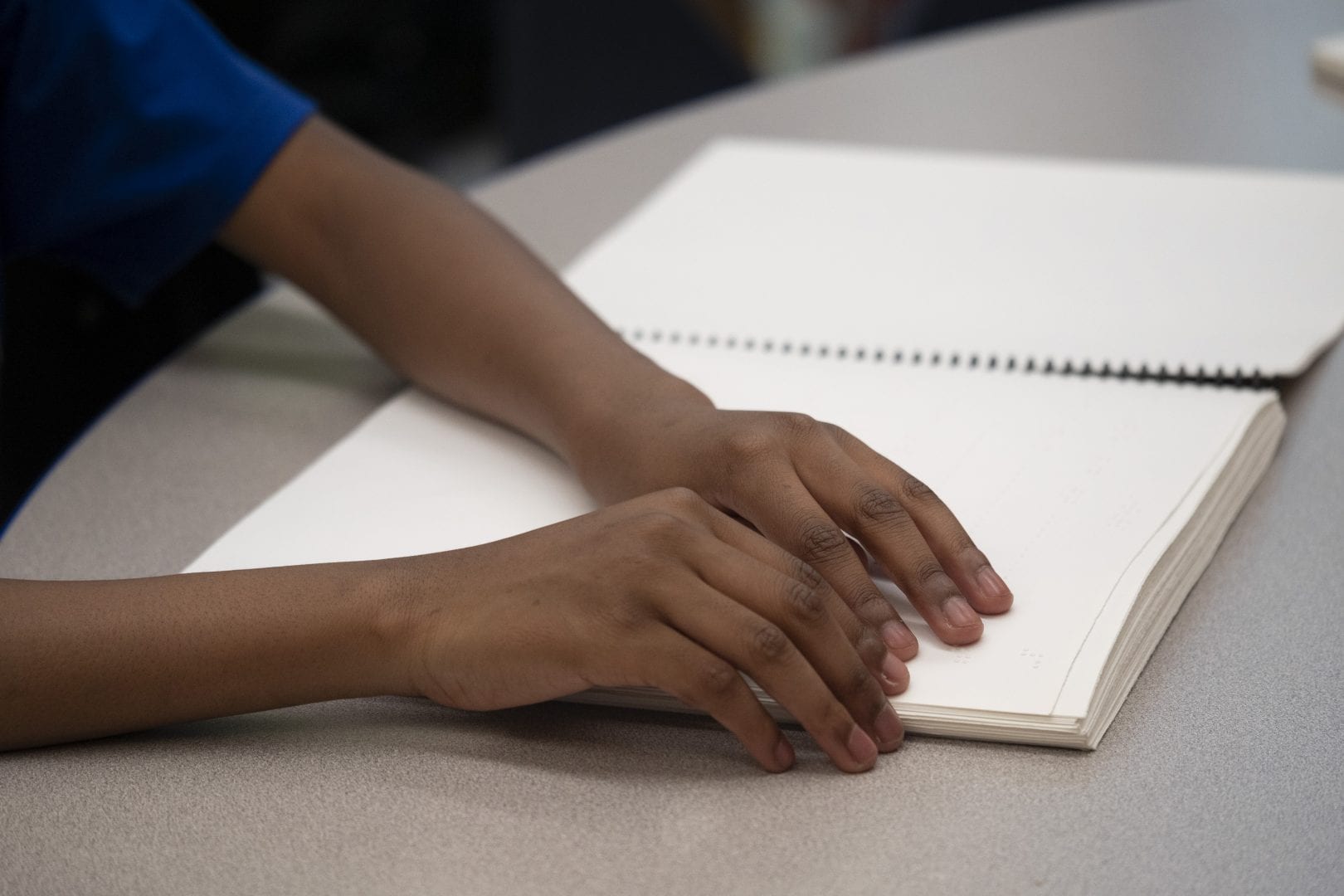 a students hands on a braille spiral bound book