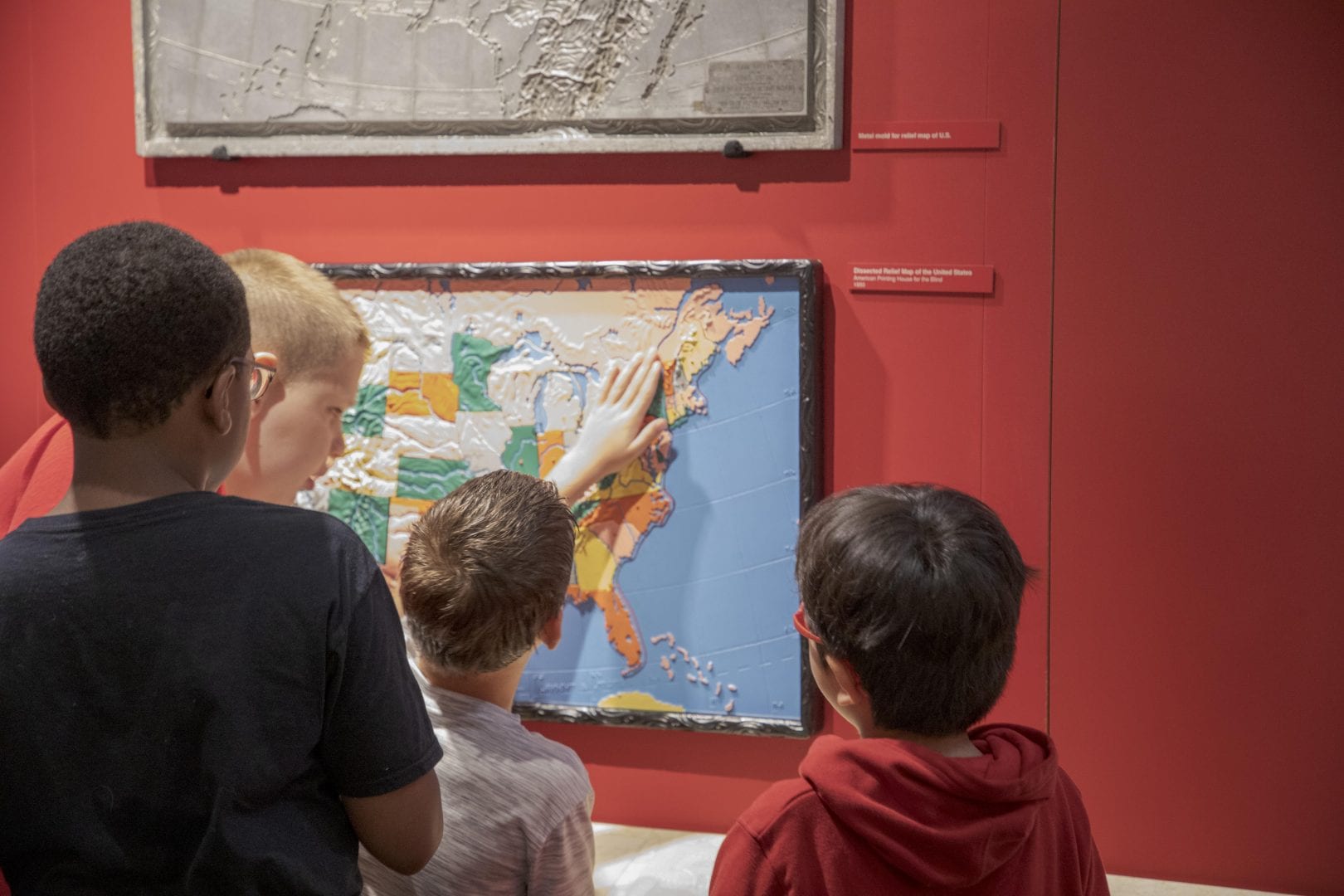 kids looking at and feeling a tactile map of the US in the APH Museum