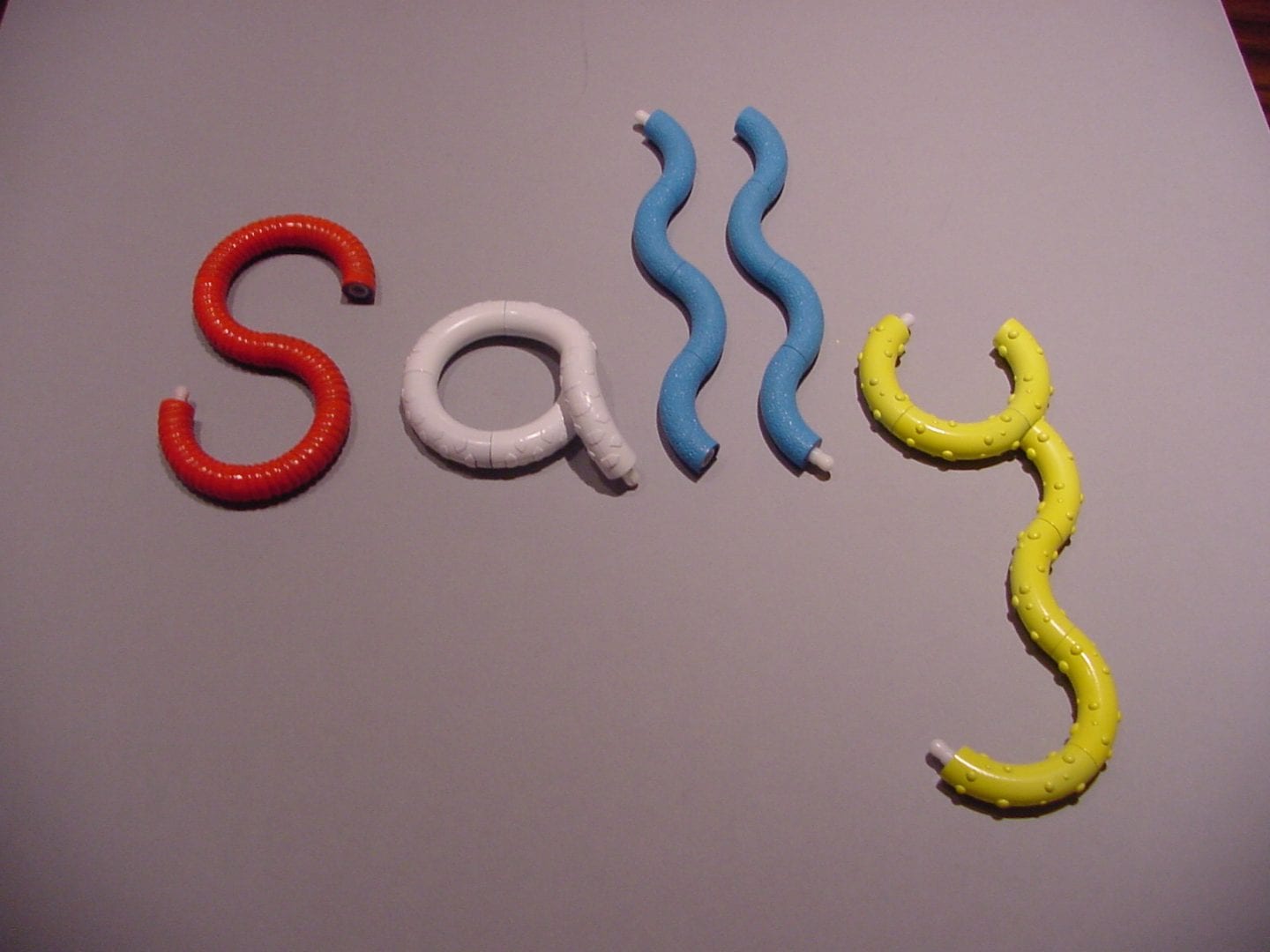 photo of tangle toys spelling out the name "sally" on a table top