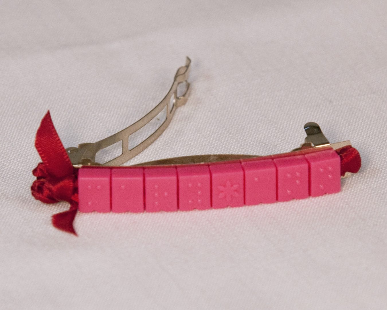 a french style barrette with pink beads as decoration sitting on a table top