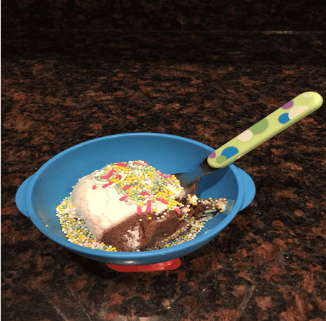a bowl of vanilla ice cream with sprinkles with a spoon