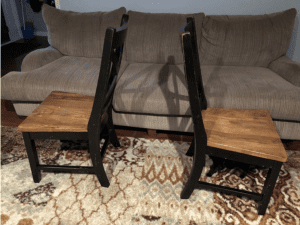 two dining room chairs back to back on a living room rug with a couple of feet between them