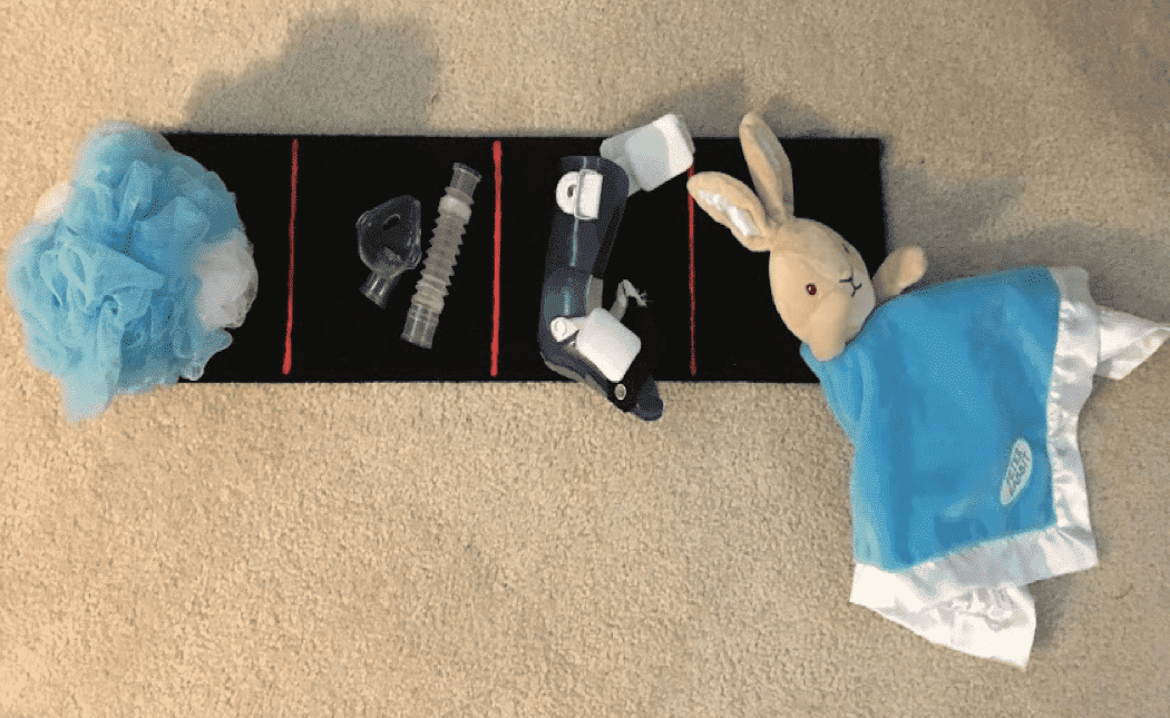 an object calendar on the floor featuring activity options including a loofa for batht ime and a stuffed rabbit for nap time