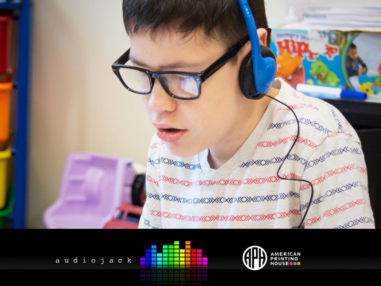 The Audiojack logo and APH logo beneath a photo of a boy engaged in listening to headphones