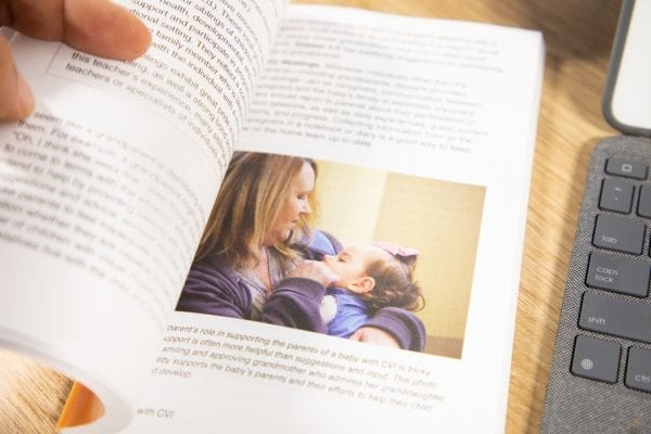 Babies with CVI book is held open to a page that includes an image of a woman and infant