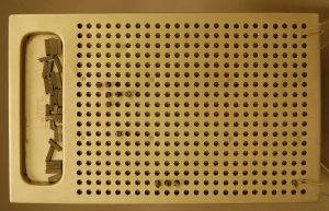 Rectangular aluminum board. There is a recessed compartment at one end holding small metal types. The rest of the board is pierced with a grid of star shaped holes.