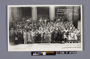 A picture of the restored black and white panorama photo. It shows a large group of people dressed in 1950s clothing standing on the steps of a building.