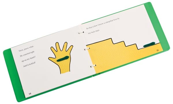 Open copy of the old version of the Caterpillar. The pages are white with black detailing and yellow textured material in the shape of a hand and a staircase. A green fuzzy caterpillar is glued to each page.