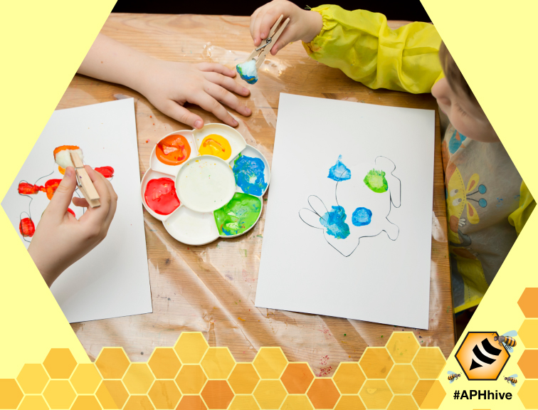 Birdseye view of young children painting pictures of bunnies with cotton balls clipped in clothespins as paintbrushes. Across the bottom is a honeycomb graphic featuring bees and the APH Hive logo.